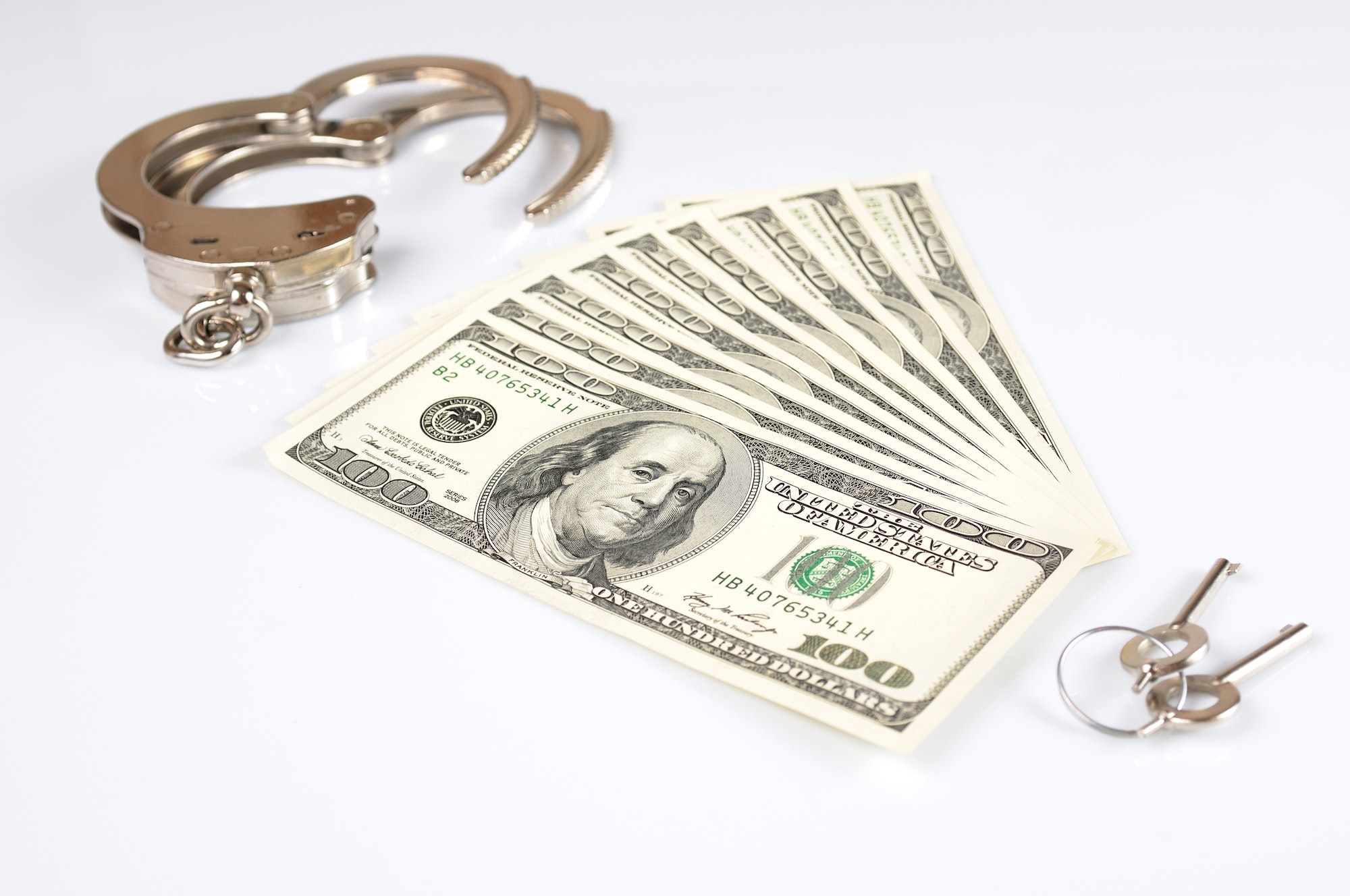 Open metal handcuffs, keys and stack of american dollars cash